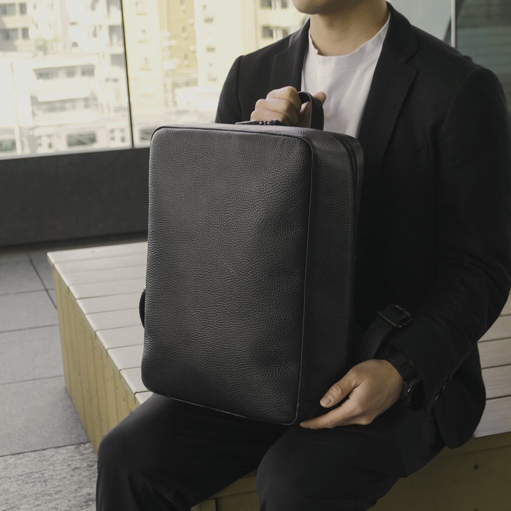 リュックを手で持つ男性
