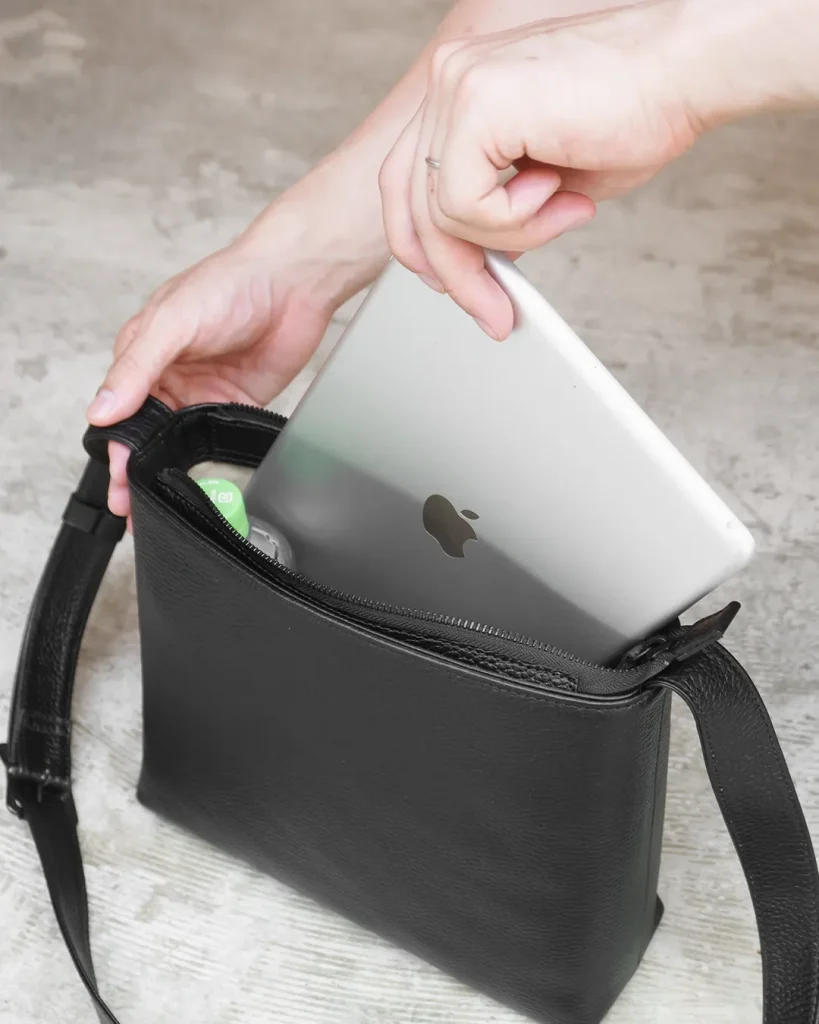 HushTugのレザーショルダーバッグにiPadを収納する様子の画像